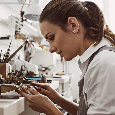 A jeweller at the bench, shaping a piece by hand